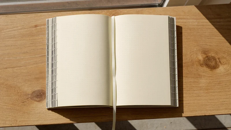Journal pointillé ouvert à plat, pages crème et signet en ruban