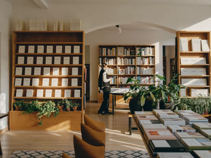 Intérieur d'une petite librairie indépendante, étagères en bois et table de lecture
